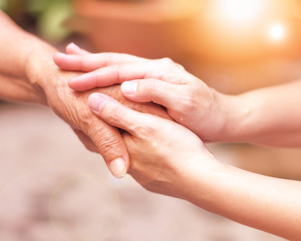 carer hand holding elder hand showing kindness