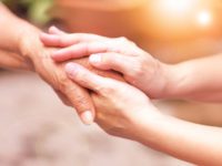 carer hand holding elder hand showing kindness to charitable trust member