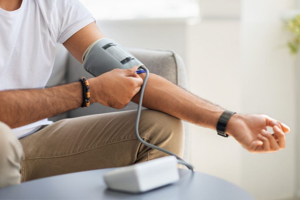 close up of man with high blood pressure using a blood pressure monitor at home
