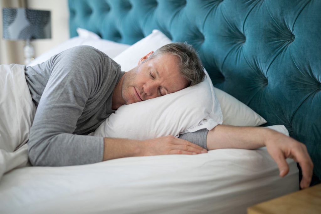 Sleep better - man sleeping on bed in bedroom at home