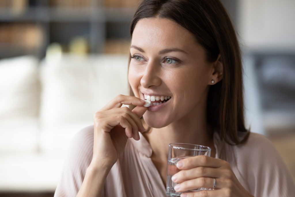 Close up smiling woman told to take medicine with food holding water glass in hand
