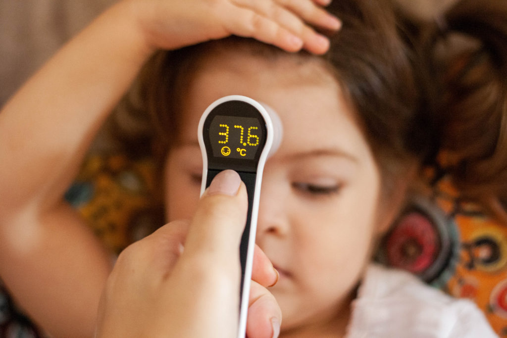 Because of the long GP wait time to get an appointment, a mum uses a digital (infrared) thermometer to check her child's temperature 