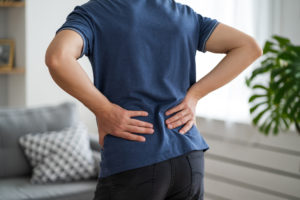 man suffering from back pain at home,