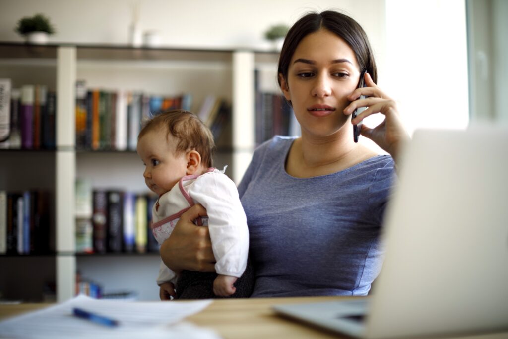 Mother on phone to pharmacist to get advice on health advice, while holding her baby.